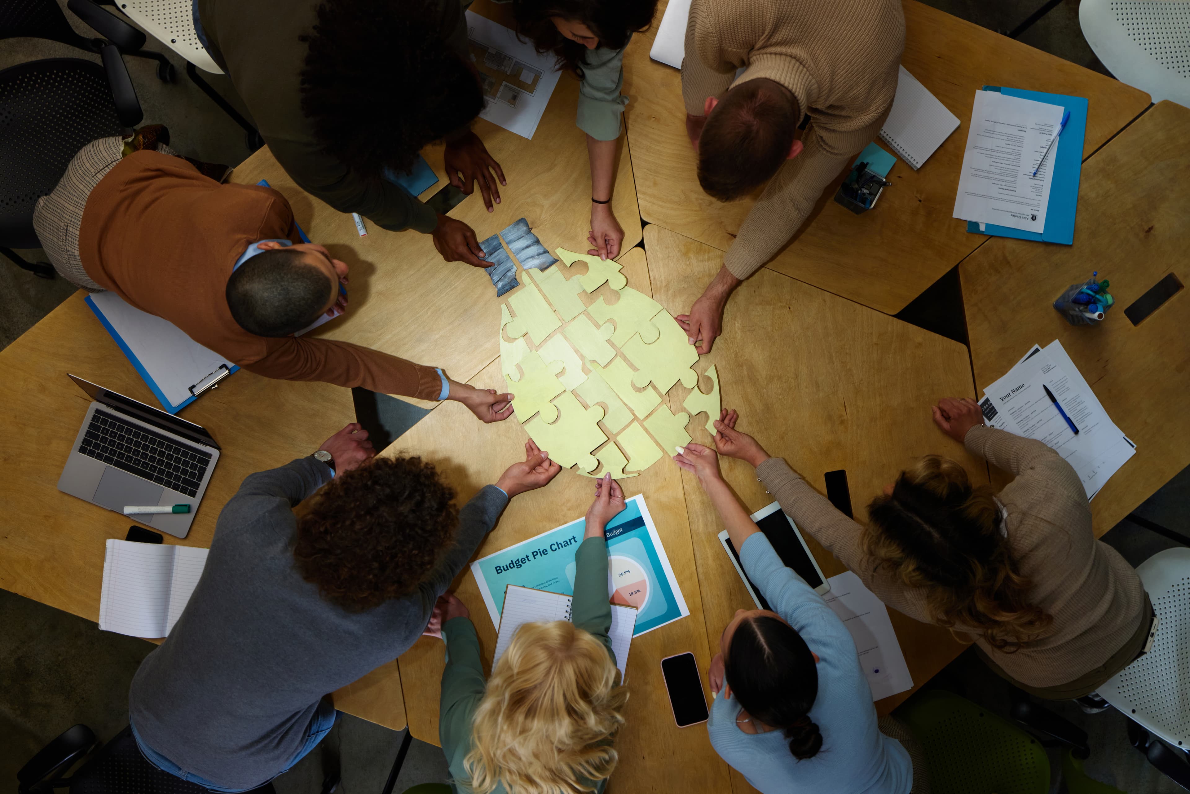 Team collaborating to assemble a brain-shaped puzzle on a table